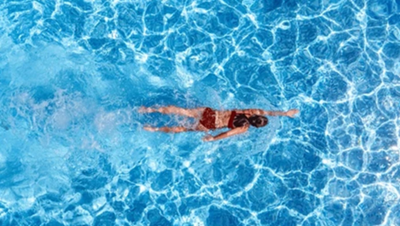 Aerial view of a swimmer doing laps in a rectangular backyard pool