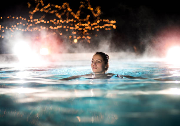 Young woman enjoying in a heated swimming pool at night.