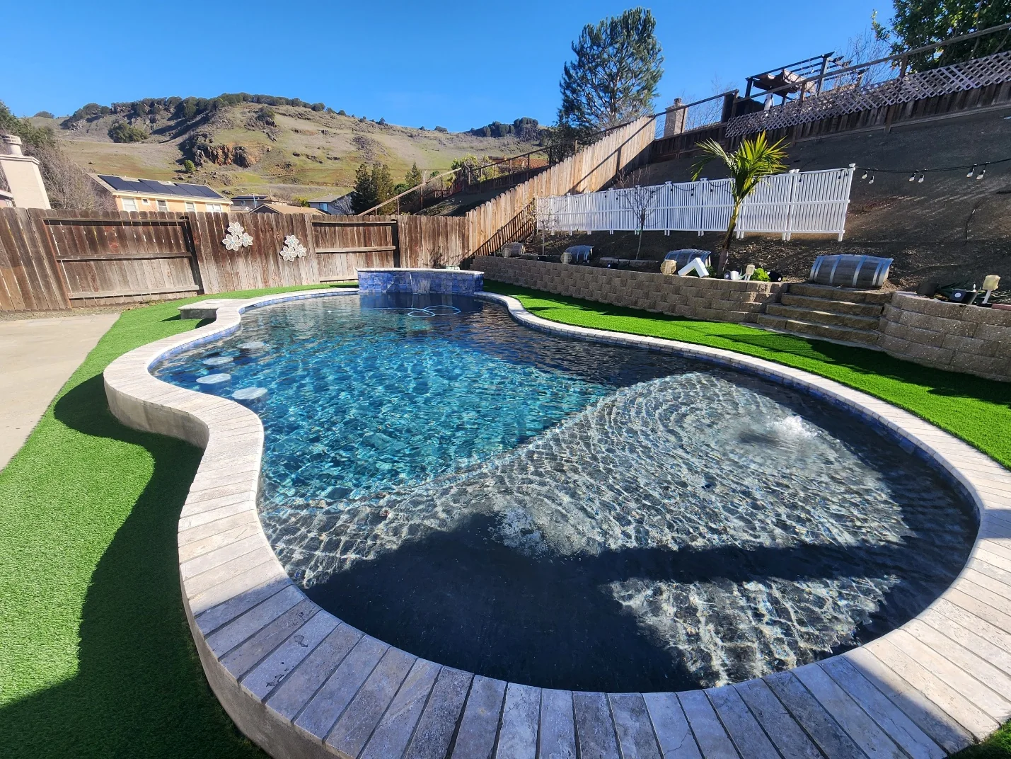 Completed freeform pool built into a sloped backyard