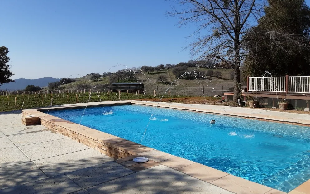 Finished pool with deck jets overlooking a vineyard