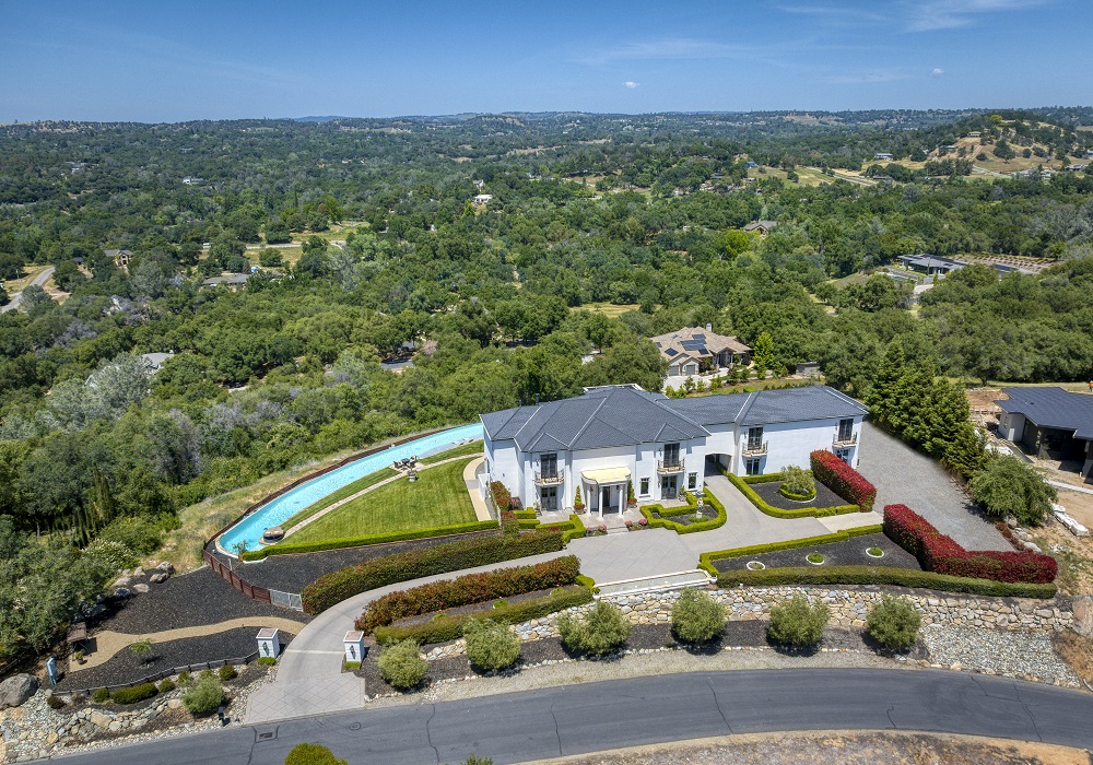 House on a hill with a large curved infinity edge pool.