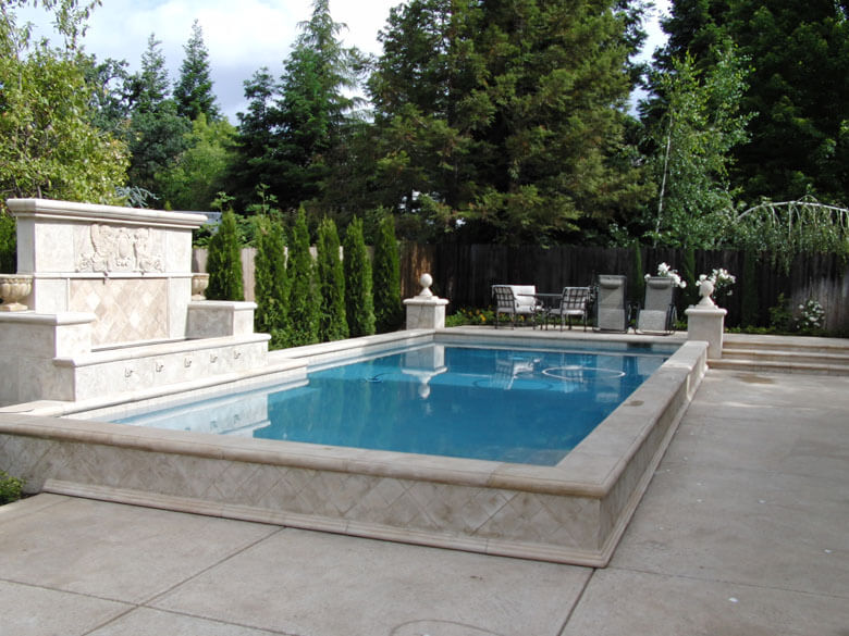 Traditional raised rectangular shaped pool with a large water feature fountain.