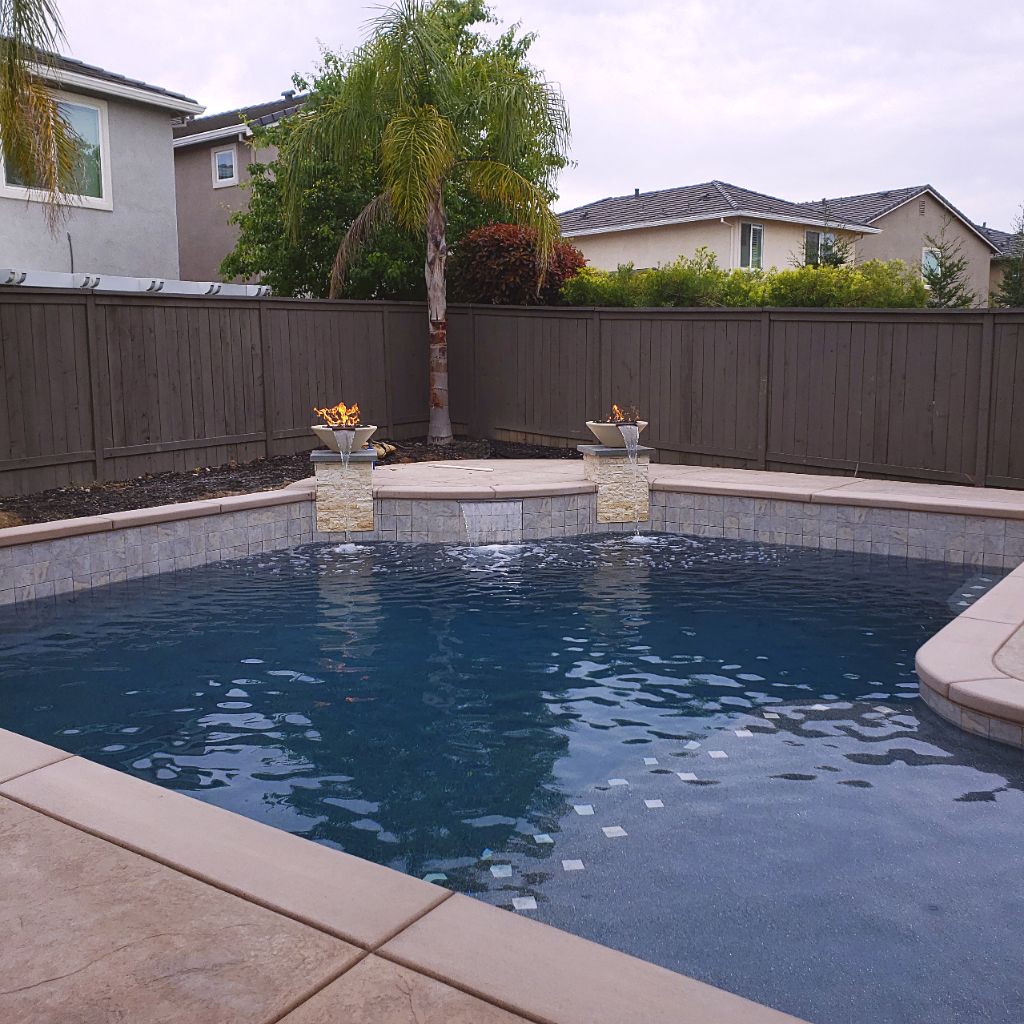 Custom shaped pool approx. 400 square feet with raised wall with two columns and fire bowl water features and Cabo shelf with step tile.