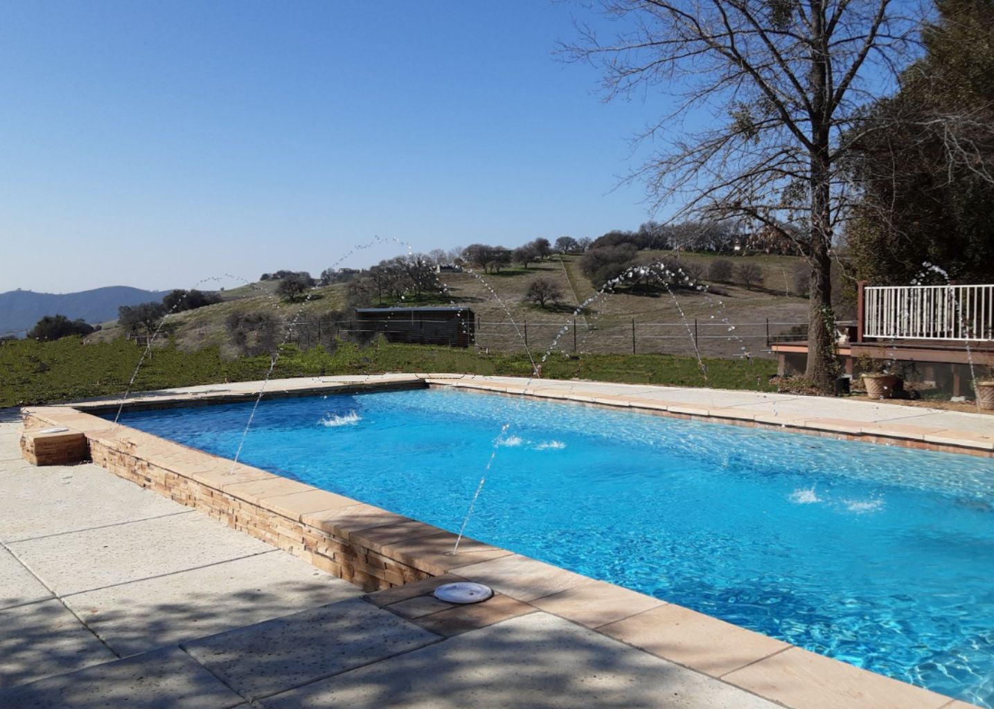 Partially raised rectangular shaped pool approx. 38' x 16' (685 square feet) with ledgerstone and deck jets.
