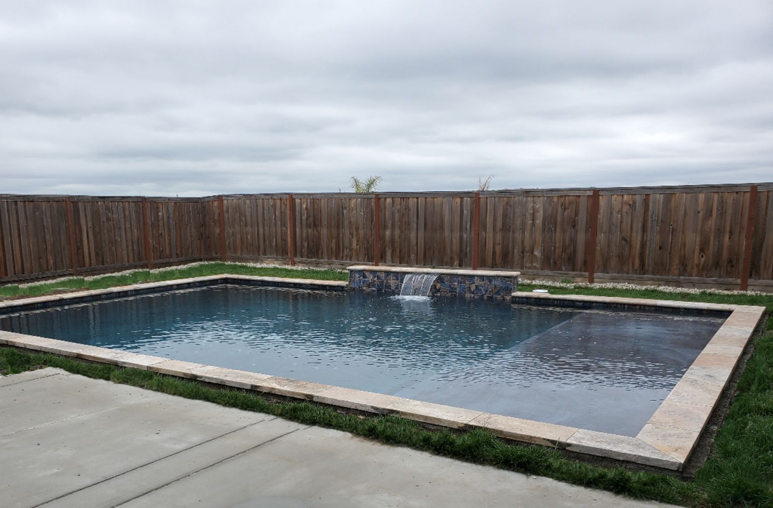 Rectangular shaped pool approx. 600 square feet with raised wall with sheer descent and travertine stone coping.