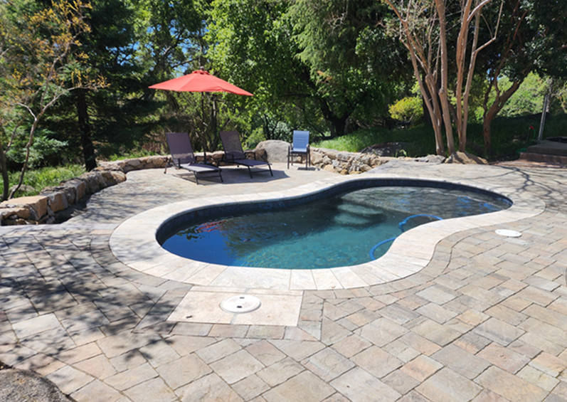 Small freeform pool with Cabo shelf, stone coping and pavers
