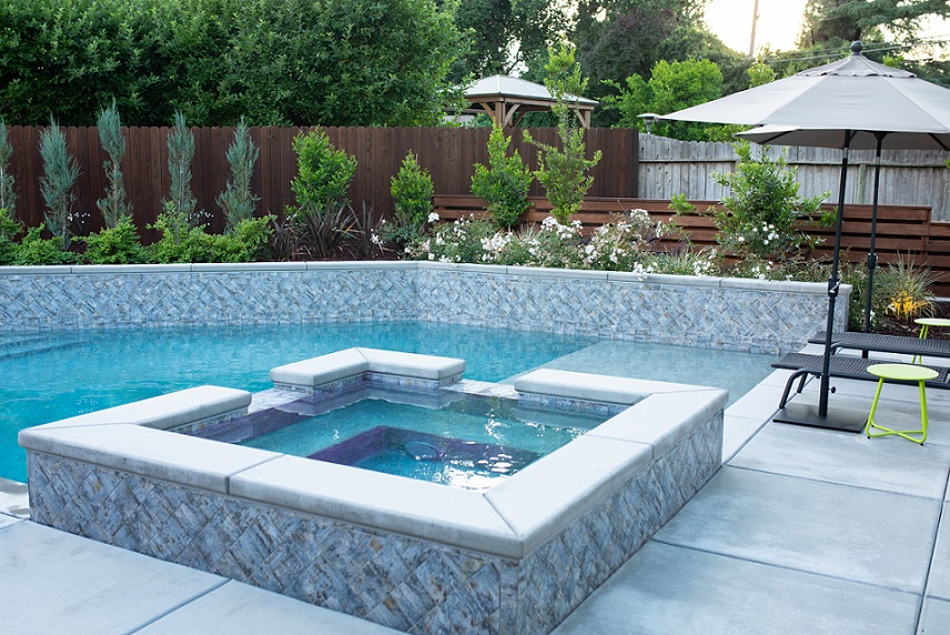 Custom shaped pool with Cabo shelf and raised spa with tile set on the diagonal