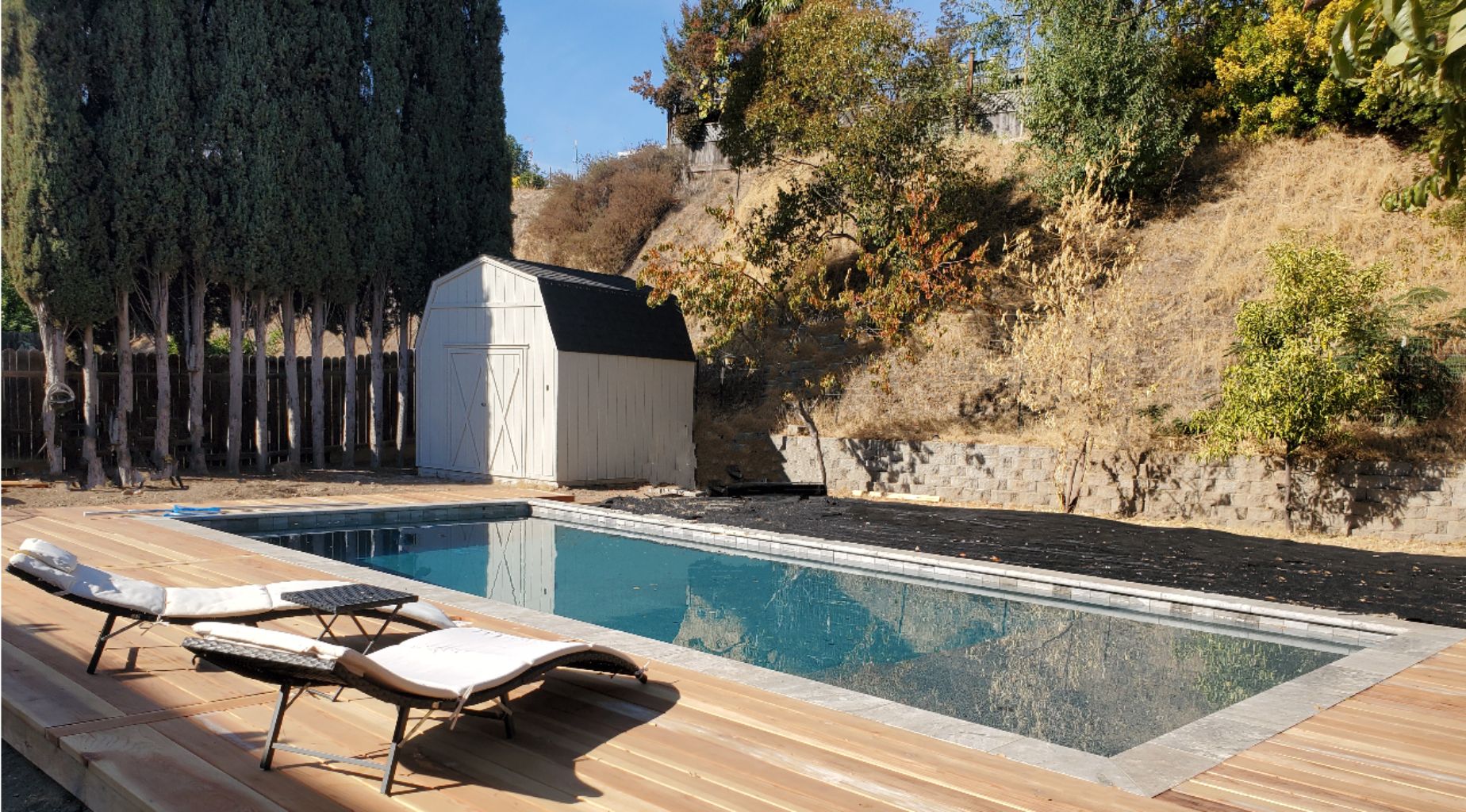 Rectangular shaped pool with stone coping and wood decking.