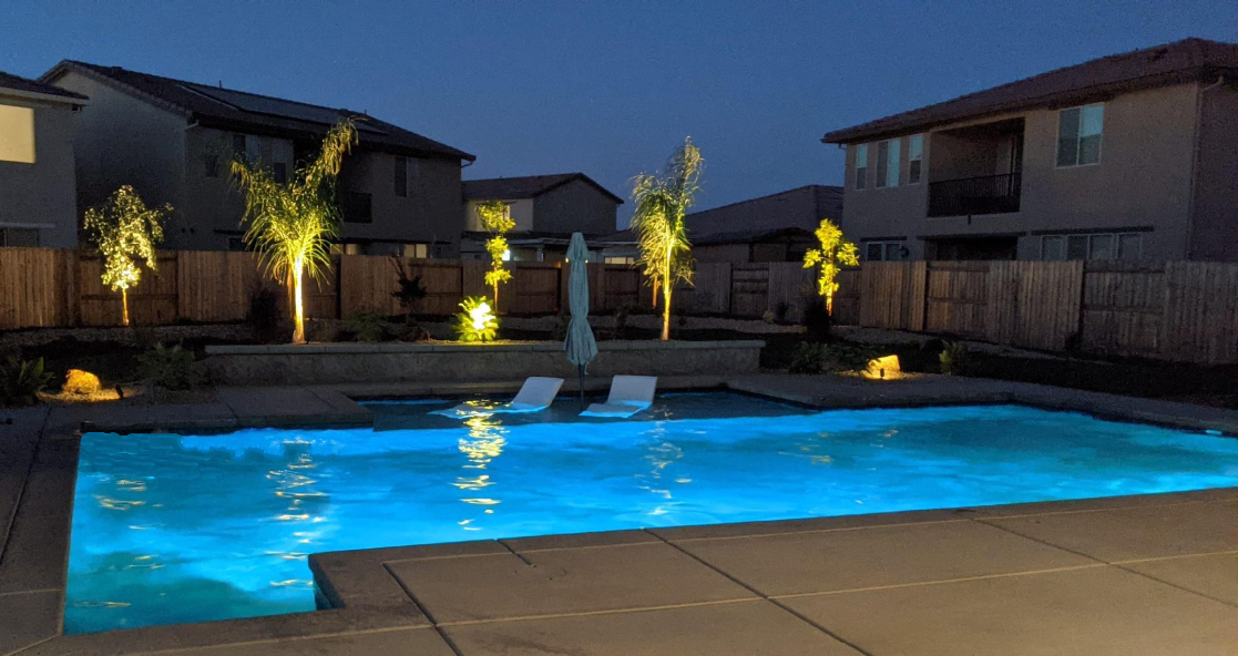 Rectangular shaped pool with large Cabo shelf with lounge chairs in evening.