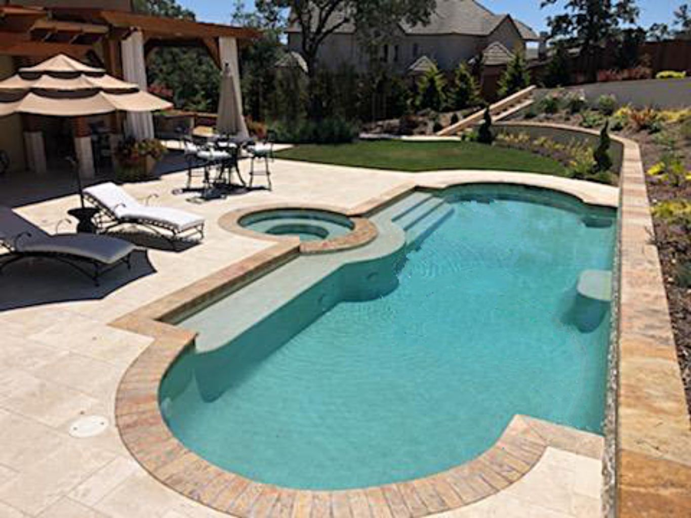 Grecian shaped pool with travetine stone coping and large Cabo shelf and spa.