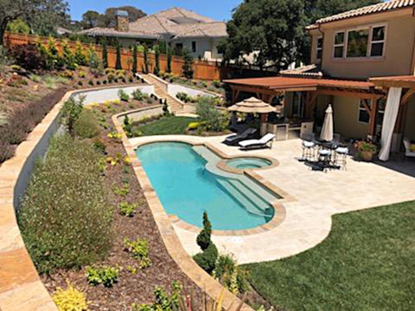 Grecian shaped pool and spa on a sloped lot with teraced planters.