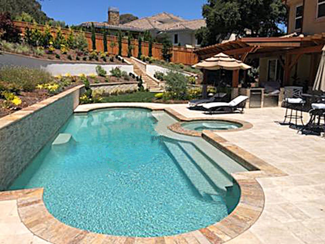 Grecian shaped pool and spa on a sloped lot with teraced planters.