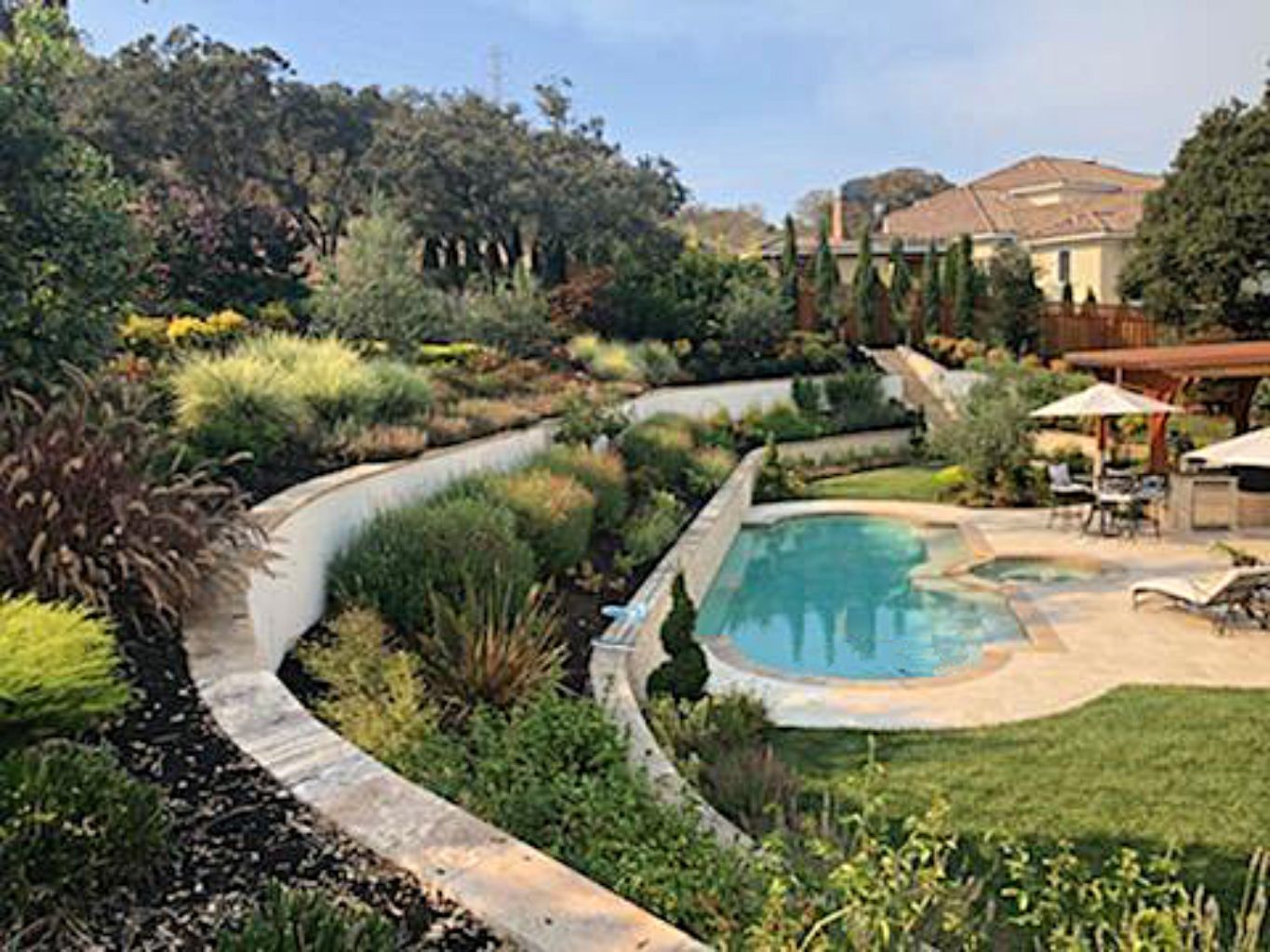 Grecian shaped pool and spa on a sloped lot with teraced planters.