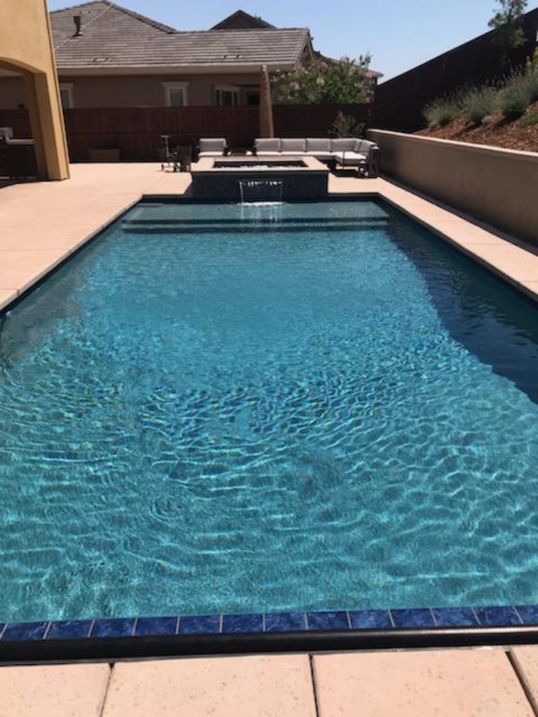 Rectangular shaped pool with an automatic pool cover, Cabo shelf and a raised spa with a sheer descent water feature.