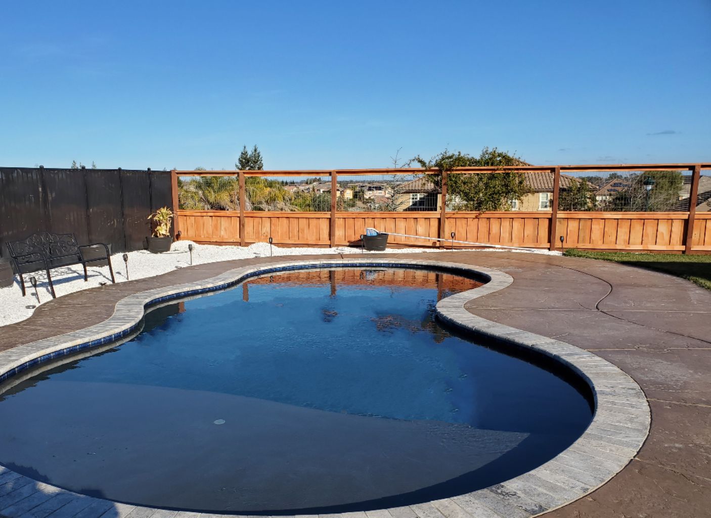 Freeform shaped pool with a large Cabo shelf and travertine stone coping.