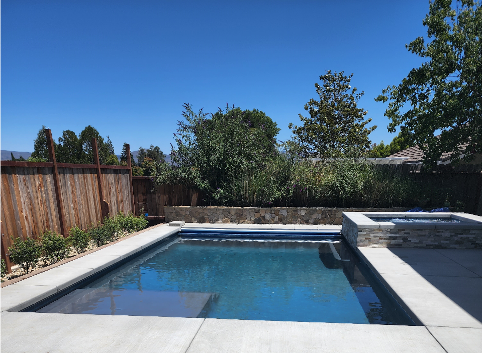 Rectangular shaped pool with an automatic pool cover and raised spa with ledgerstone and a stone faced retaining wall planter.