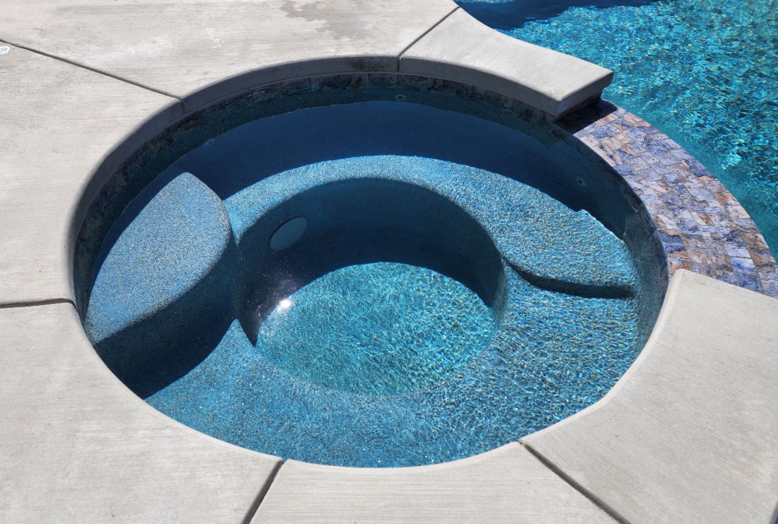 Round spa with a tiled spillway.
