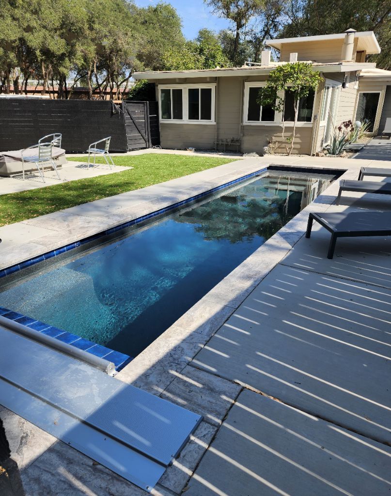 Small lap pool 27' x 7' with an automatic pool cover wtih an aluminum lid and travertine stone coping and concrete decking in Granite Bay.
