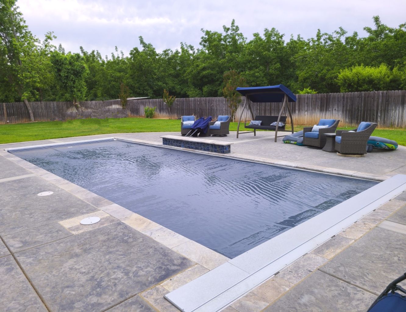 Rectangular shaped pool with automatic pool cover with an aluminum lid and travertine stone coping.