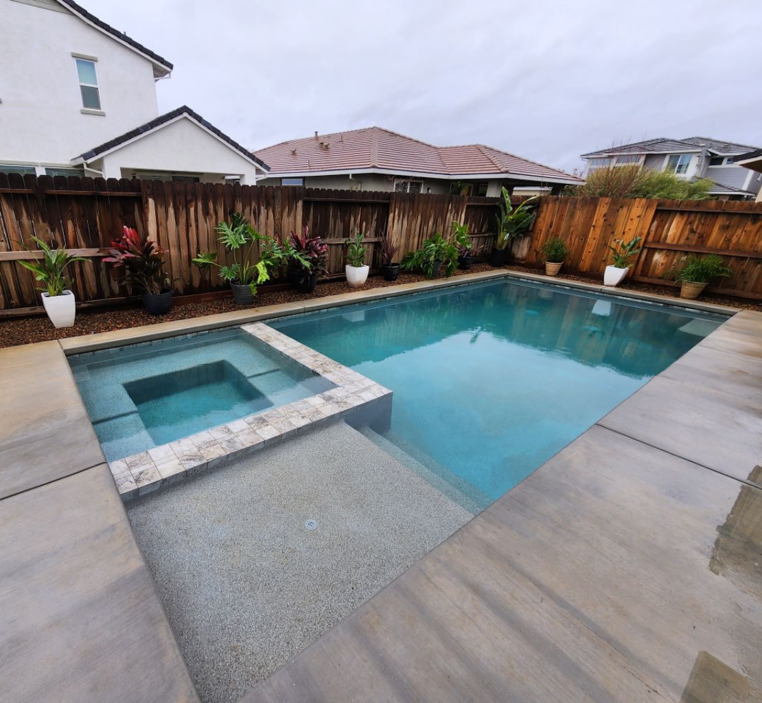 Rectangular shaped pool with a Cabo shelf and a spa and concrete decking and coping.