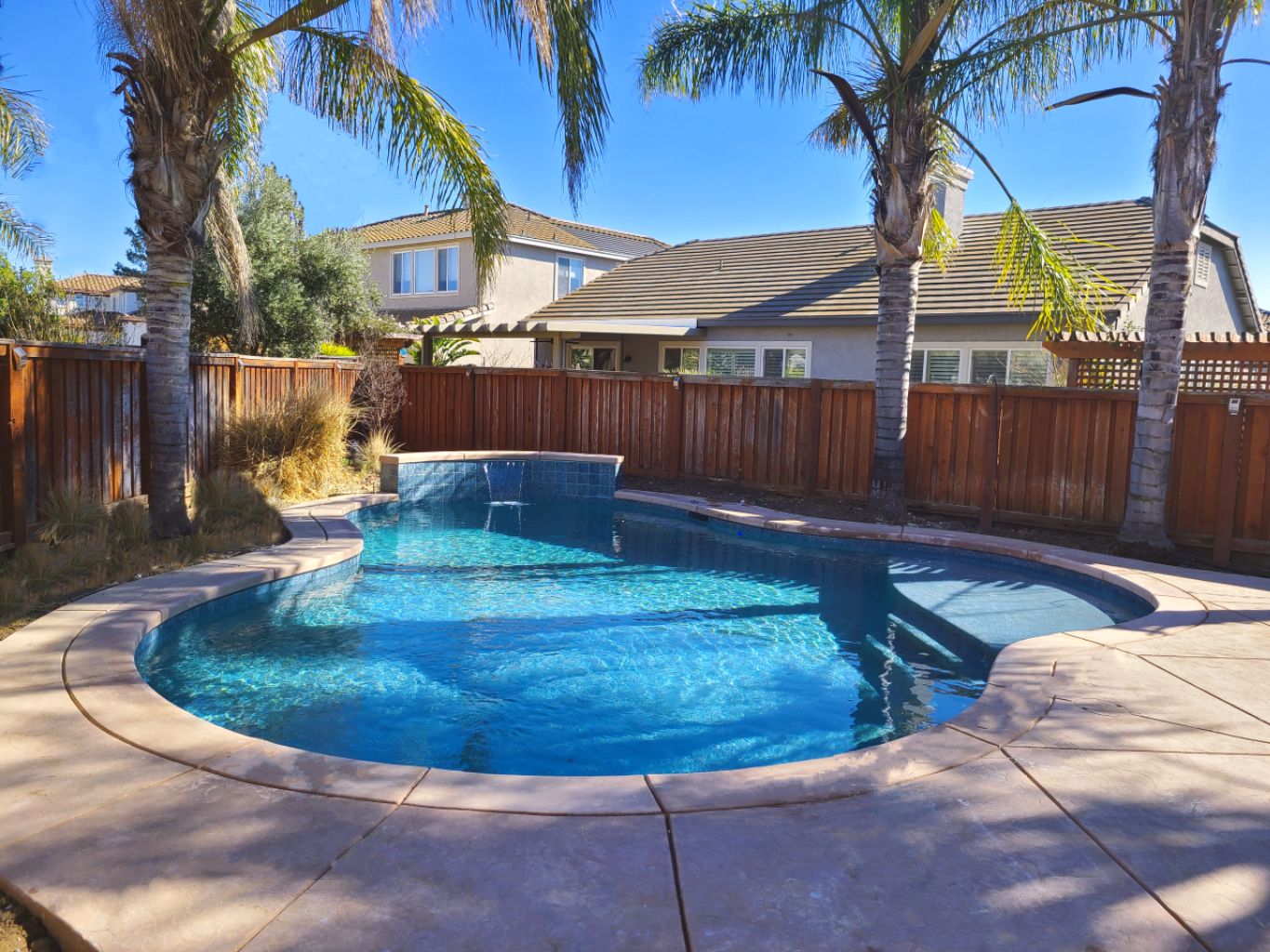 Freeform shaped pool with raised wall with sheer descent water feature.