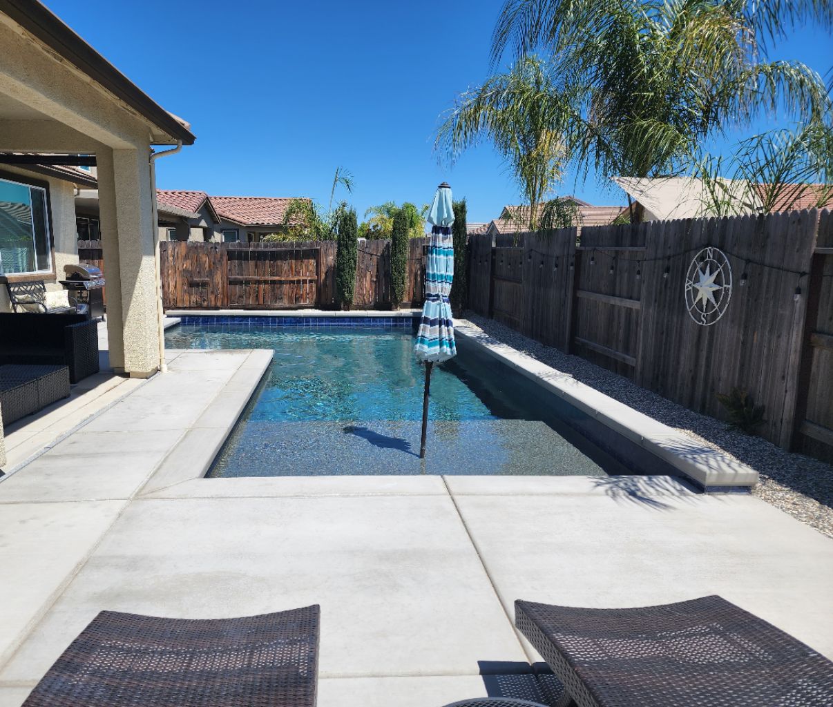 L-shaped custom pool with a Cabo shelf and concrete coping and decking.