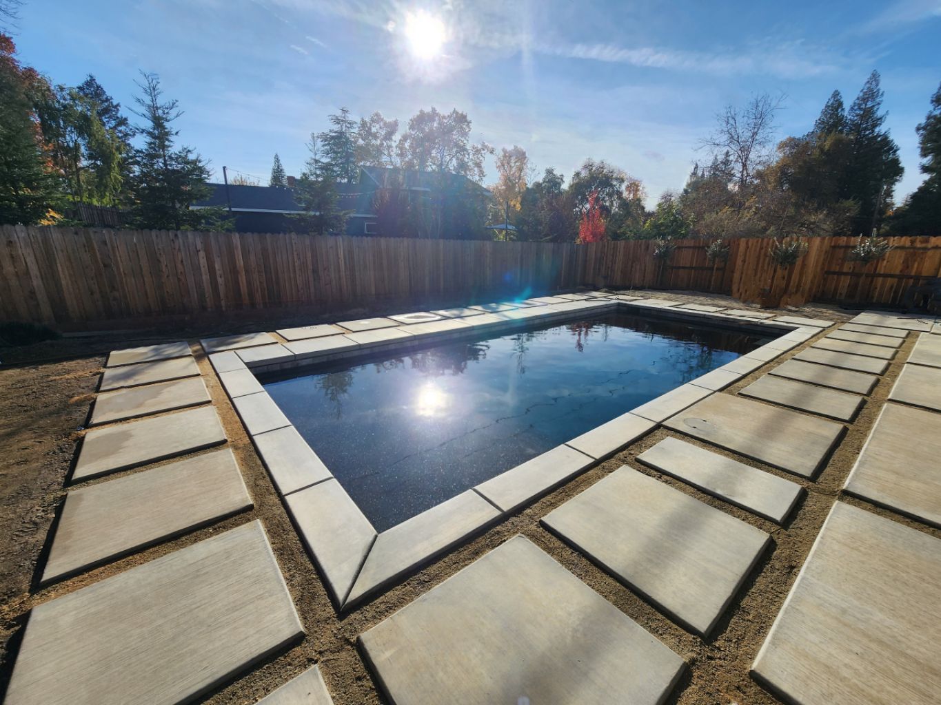 Rectangular shaped pool with concrete coping and custom sized concrete pavers before turf is added.