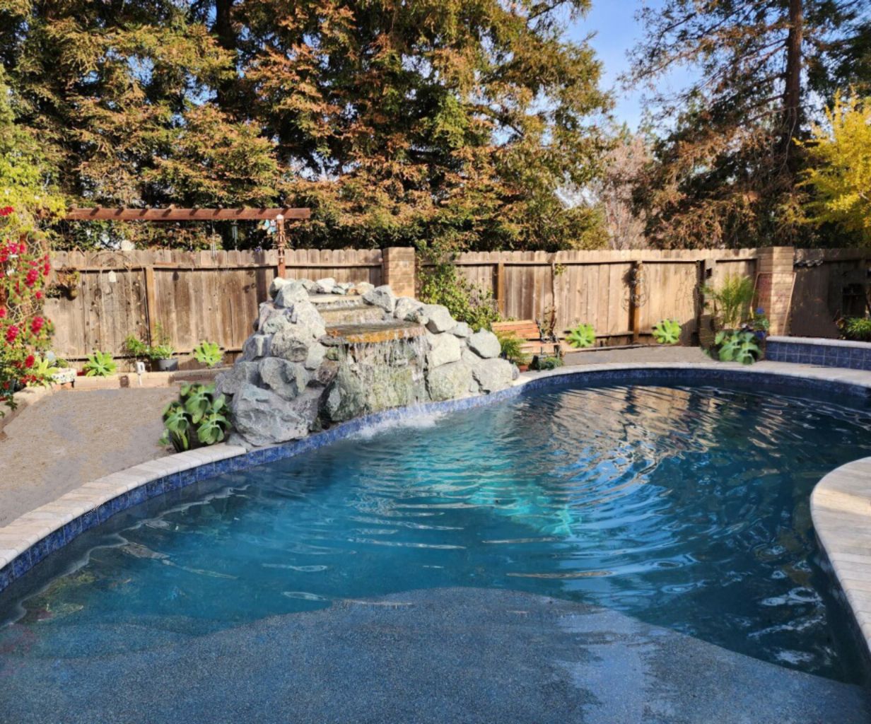 Freeform shaped pool with a rock waterfall and a Cabo shelf.