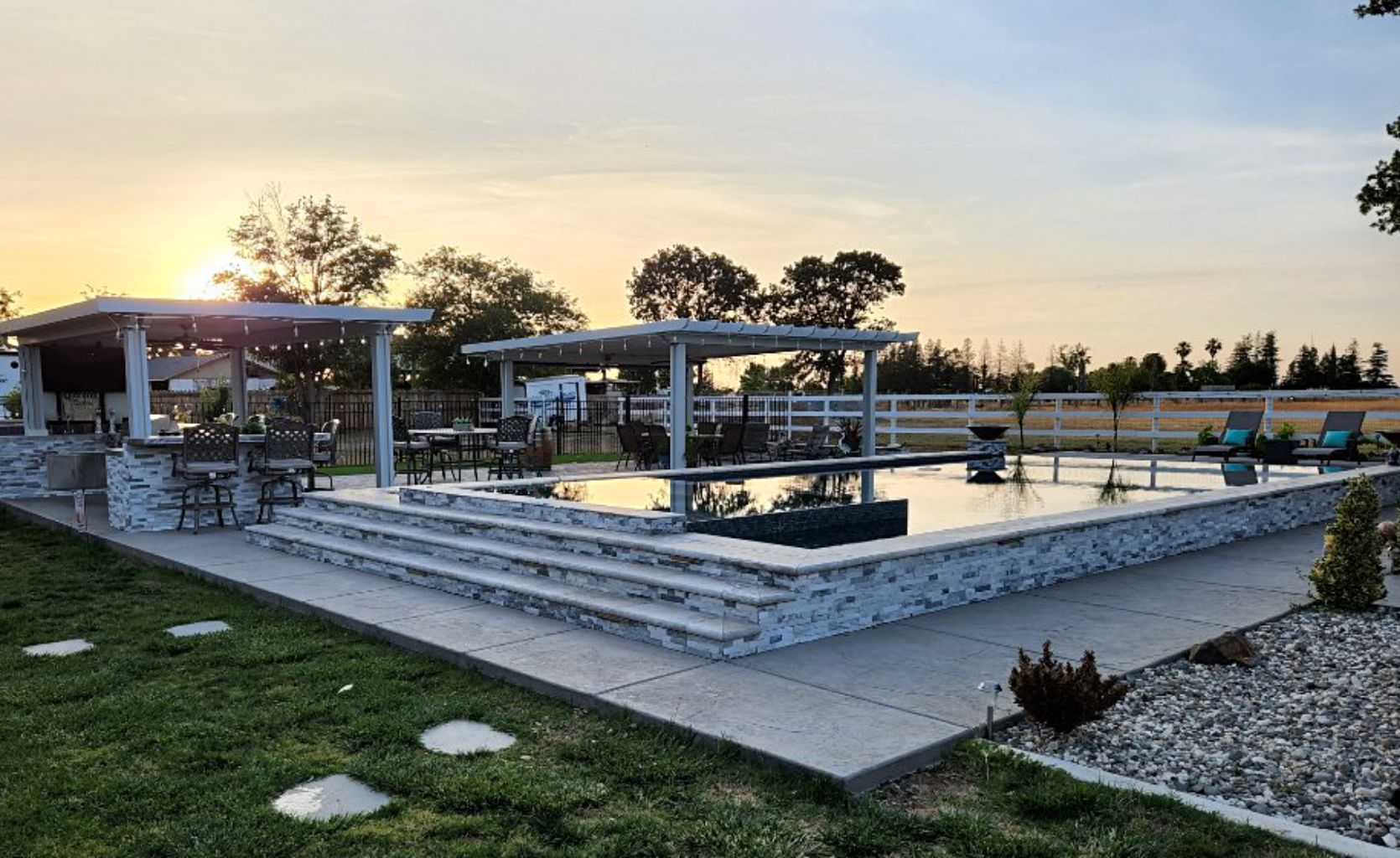 Raised pool with ledgerstone facing and spa and two large loggias for an outdoor kitchen and sitting area.