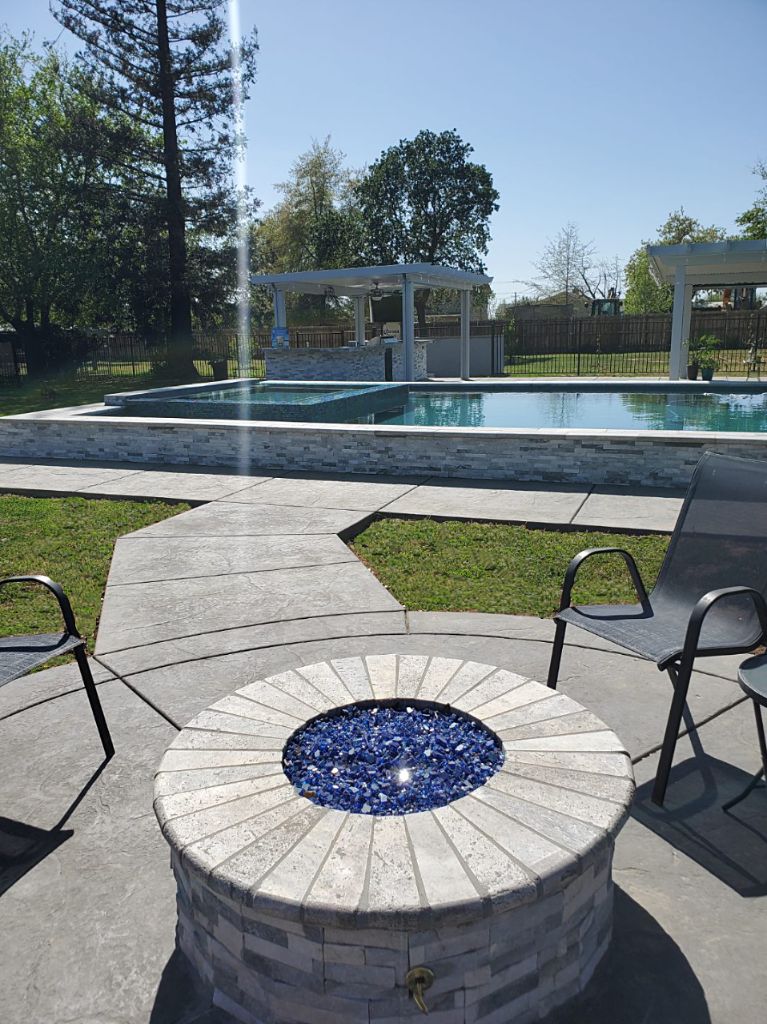 Round built-in fire pit with raised pool with ledgerstone facing and spa.