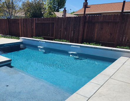 Rectangular shaped pool with larged bumped out Cabo shelf and raised wall with two sheer descent water features.