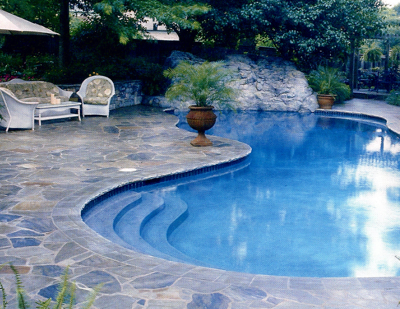 Freeform shaped pool with flagstone decking and large rock waterfall.
