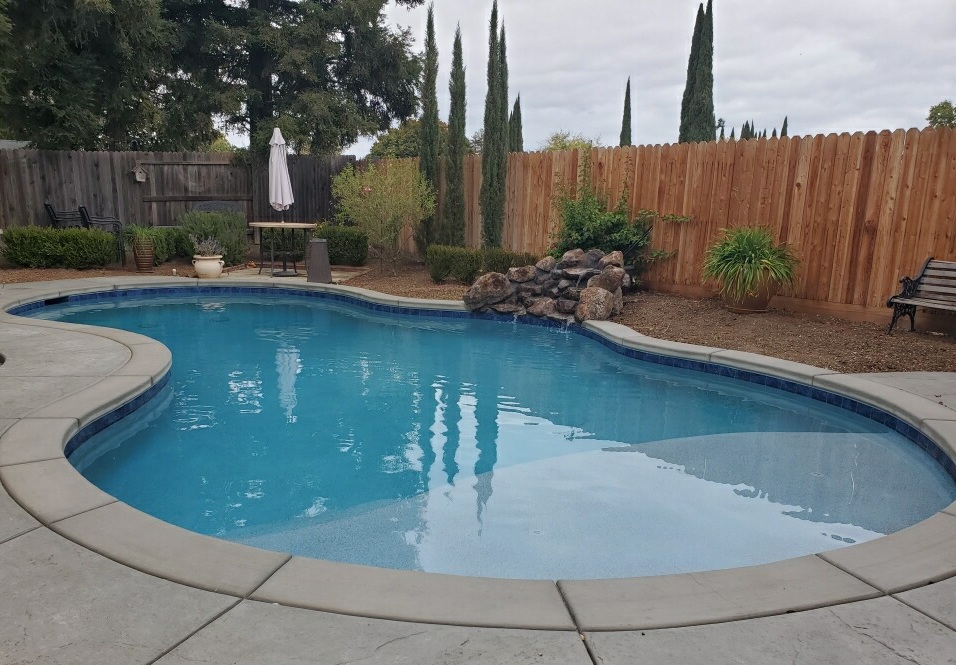 Freeform shaped pool with small rock waterfall and Cabo shelf
