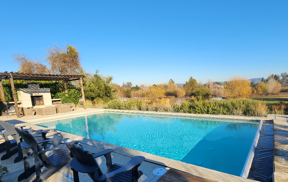 Rectangular pool with automatic pool cover and built in fireplace next to pool.