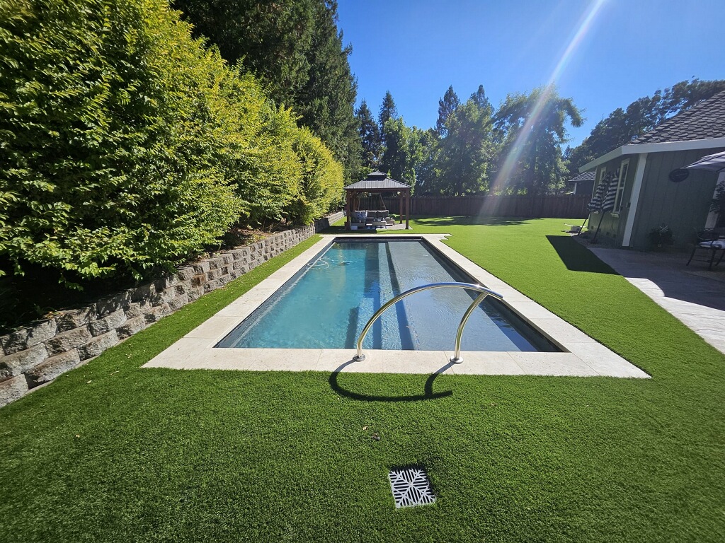 Rectangular pool with stone coping and landscaped backyard