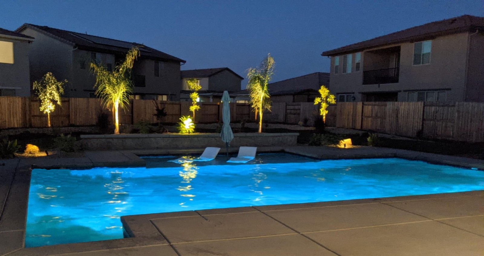 Rectangular pool with large Cabo shelf and lounge chairs at dusk