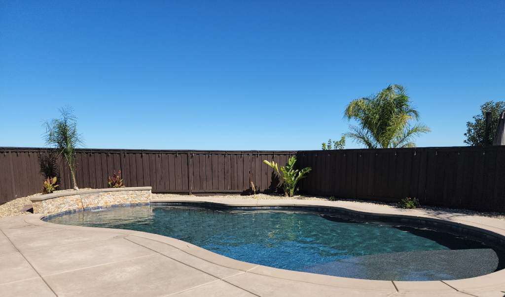 Freeform shaped pool with raised bond beam, sheer descent water feature, and natural stone coping