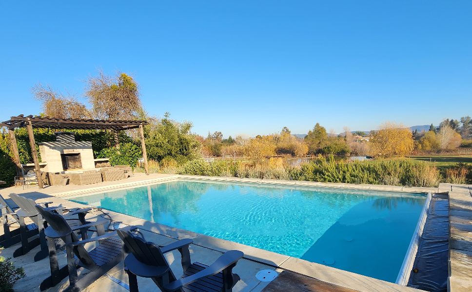 Rectangular pool with automatic pool cover and built-in fireplace next to the pool