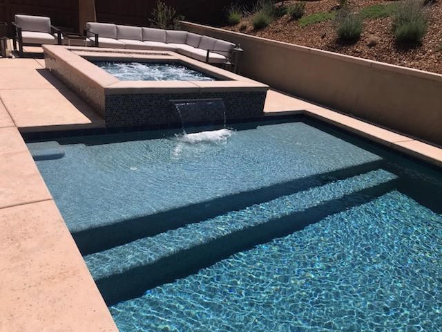 Raised spa with sheer descent into rectangular pool with Cabo shelf
